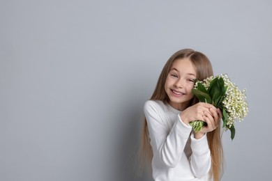 Photo of Girl with bouquet of beautiful lily-of-the-valley flowers on light grey background. Space for text