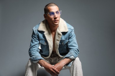 Photo of Fashionable portrait of handsome man in stylish outfit on chair against grey background