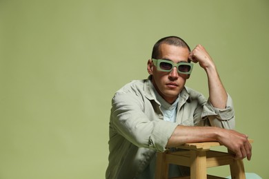 Photo of Fashionable portrait of handsome man in stylish outfit on green background, space for text