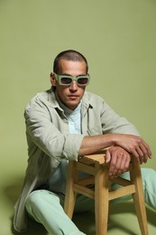 Photo of Fashionable portrait of handsome man in stylish outfit on green background