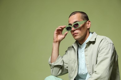 Photo of Fashionable portrait of handsome man in stylish outfit on green background, space for text