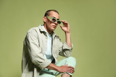 Photo of Fashionable portrait of handsome man in stylish outfit on green background, space for text