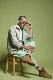 Photo of Fashionable portrait of handsome man in stylish outfit on green background
