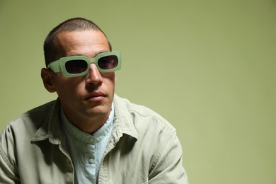 Photo of Fashionable portrait of handsome man in stylish outfit on green background, space for text