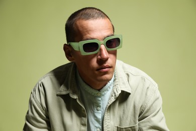 Photo of Fashionable portrait of handsome man in stylish outfit on green background