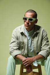 Photo of Fashionable portrait of handsome man in stylish outfit on green background