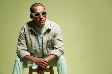 Photo of Fashionable portrait of handsome man in stylish outfit on green background, space for text