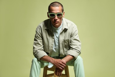Photo of Fashionable portrait of handsome man in stylish outfit on green background