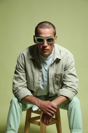 Photo of Fashionable portrait of handsome man in stylish outfit on green background