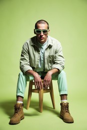 Photo of Fashionable portrait of handsome man in stylish outfit on green background