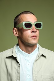 Photo of Fashionable portrait of handsome man in stylish outfit on green background
