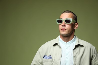 Photo of Fashionable portrait of handsome man in stylish outfit on green background, space for text