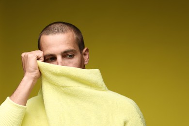 Photo of Fashionable portrait of handsome man in stylish outfit on olive background, space for text