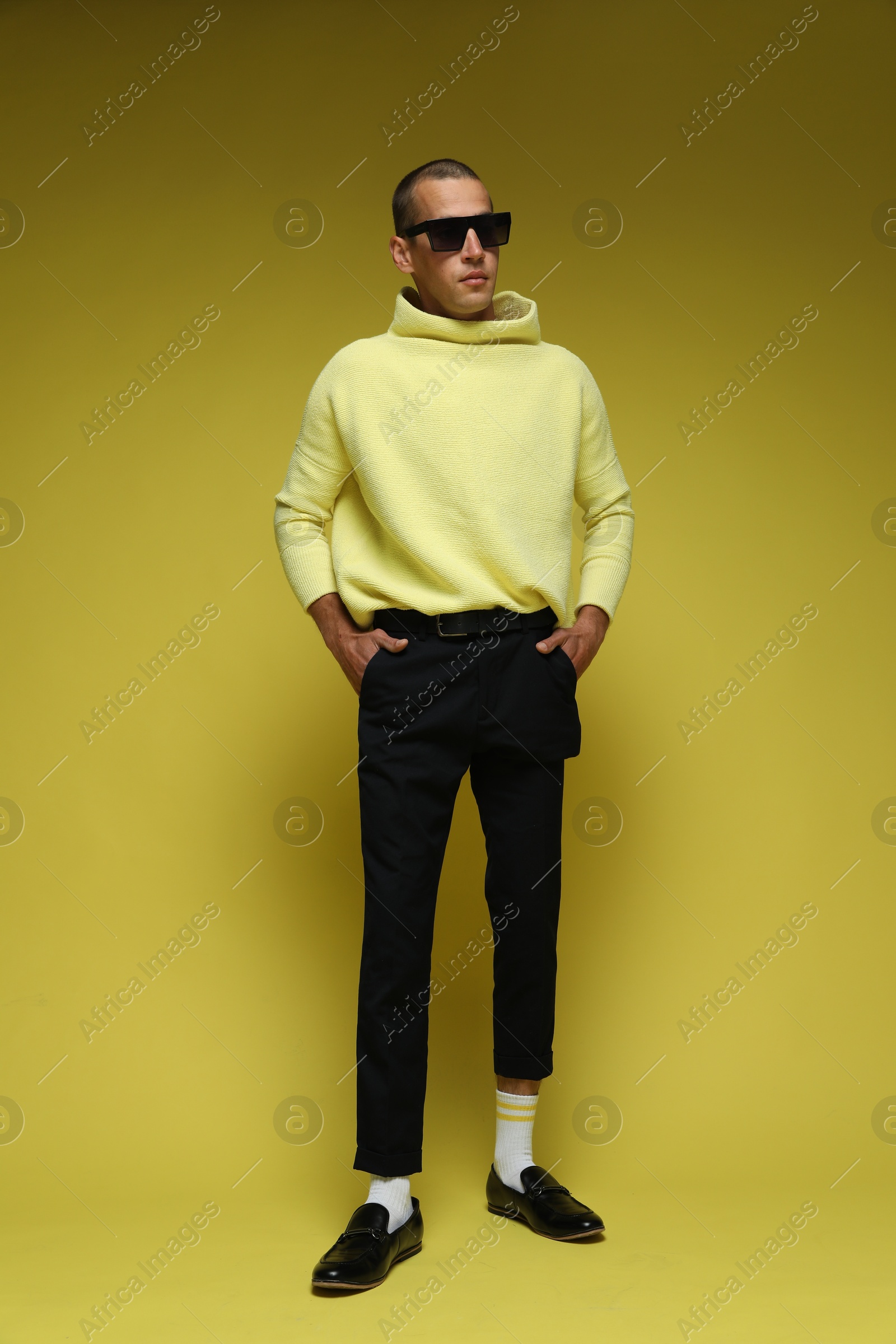 Fashionable portrait of handsome man in stylish outfit on yellow background Photo of Fashionable portrait of handsome man in stylish outfit on yellow background