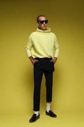 Photo of Fashionable portrait of handsome man in stylish outfit on yellow background