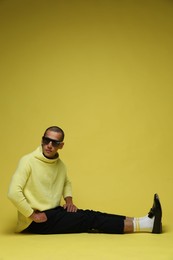 Photo of Fashionable portrait of handsome man in stylish outfit on yellow background