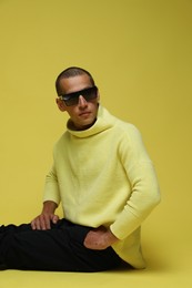 Photo of Fashionable portrait of handsome man in stylish outfit on yellow background