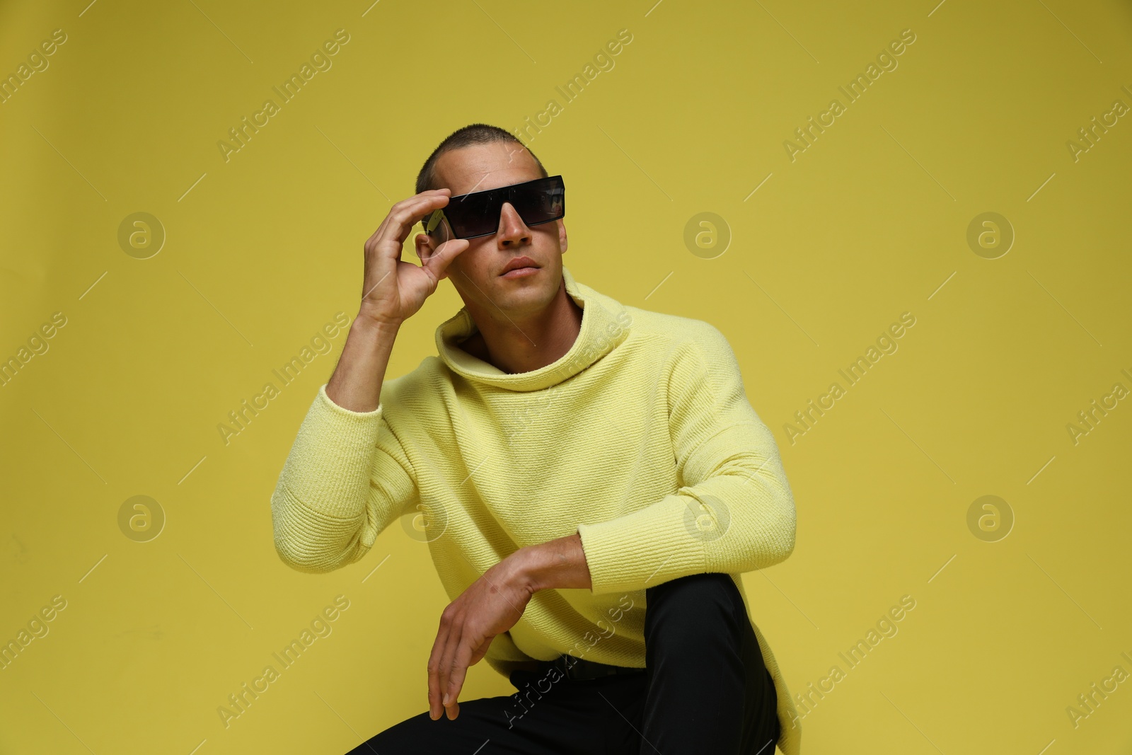 Fashionable portrait of handsome man in stylish outfit on yellow background Photo of Fashionable portrait of handsome man in stylish outfit on yellow background