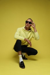 Photo of Fashionable portrait of handsome man in stylish outfit on yellow background