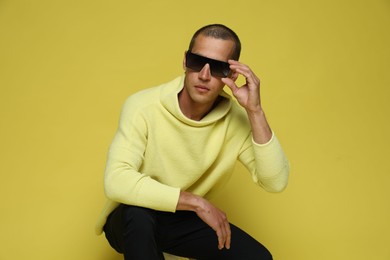 Photo of Fashionable portrait of handsome man in stylish outfit on yellow background