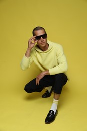 Photo of Fashionable portrait of handsome man in stylish outfit on yellow background