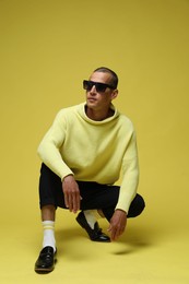 Photo of Fashionable portrait of handsome man in stylish outfit on yellow background