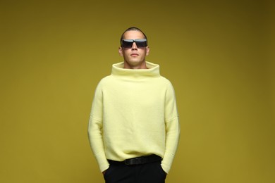 Photo of Fashionable portrait of handsome man in stylish outfit on olive background
