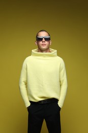Photo of Fashionable portrait of handsome man in stylish outfit on olive background