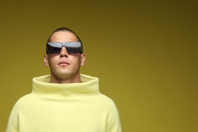 Photo of Fashionable portrait of handsome man in stylish outfit on olive background, space for text
