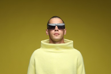 Photo of Fashionable portrait of handsome man in stylish outfit on olive background