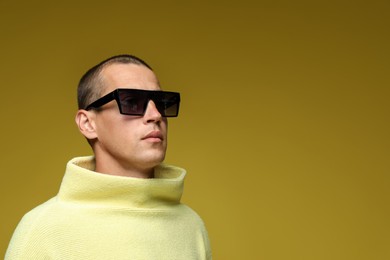 Photo of Fashionable portrait of handsome man in stylish outfit on olive background, space for text