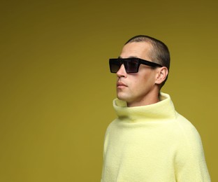 Photo of Fashionable portrait of handsome man in stylish outfit on olive background, space for text