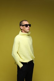 Photo of Fashionable portrait of handsome man in stylish outfit on olive background