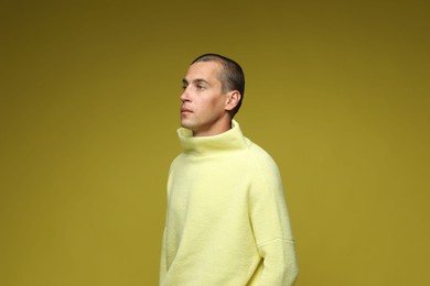 Photo of Fashionable portrait of handsome man in stylish outfit on olive background