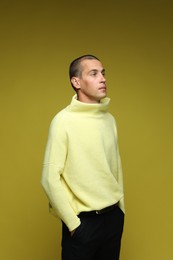 Photo of Fashionable portrait of handsome man in stylish outfit on olive background