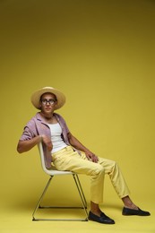Photo of Fashionable portrait of handsome man in stylish outfit on yellow background