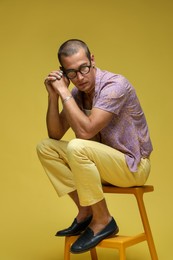 Photo of Fashionable portrait of handsome man in stylish outfit on color background