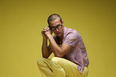 Photo of Fashionable portrait of handsome man in stylish outfit on olive background