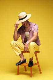 Photo of Fashionable portrait of handsome man in stylish outfit on yellow background