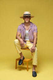 Photo of Fashionable portrait of handsome man in stylish outfit on yellow background