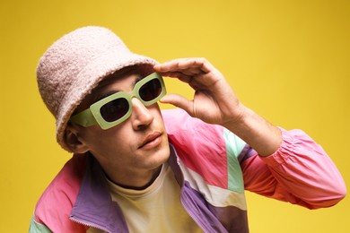 Photo of Fashionable portrait of handsome man in stylish outfit on yellow background