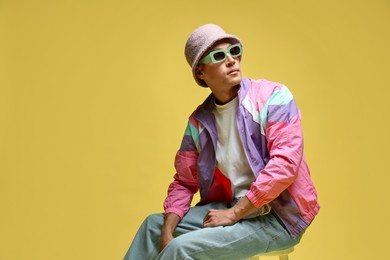 Photo of Fashionable portrait of handsome man in stylish outfit on yellow background, space for text