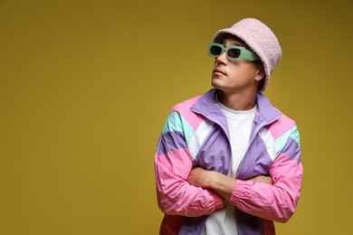 Photo of Fashionable portrait of handsome man in stylish outfit on olive background, space for text