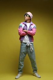 Photo of Fashionable portrait of handsome man in stylish outfit on olive background