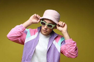 Photo of Fashionable portrait of handsome man in stylish outfit on olive background