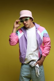 Photo of Fashionable portrait of handsome man in stylish outfit on olive background