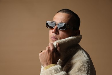 Photo of Fashionable portrait of handsome man in stylish outfit on brown background, space for text