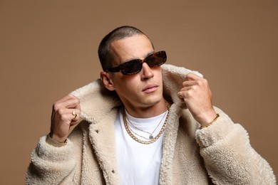 Photo of Fashionable portrait of handsome man in stylish outfit on brown background