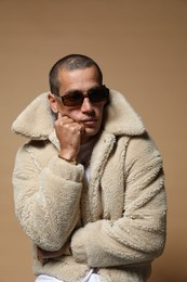 Photo of Fashionable portrait of handsome man in stylish outfit on brown background