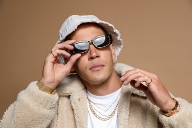 Photo of Fashionable portrait of handsome man in stylish outfit on brown background